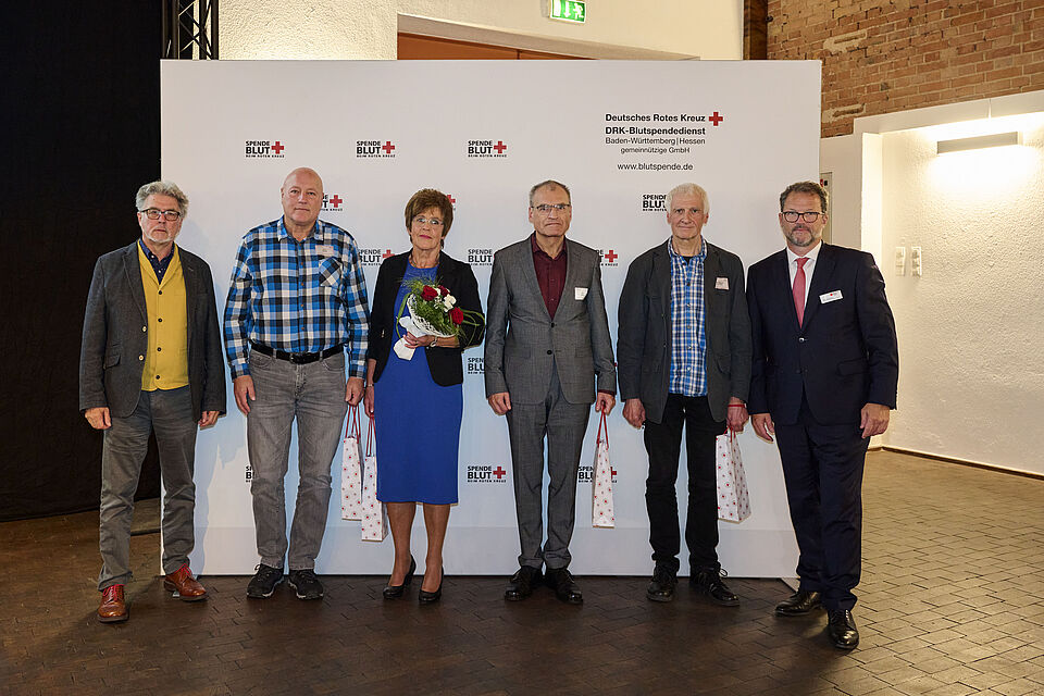 fünf Männer und eine Frau stehen vor einem DRK Display